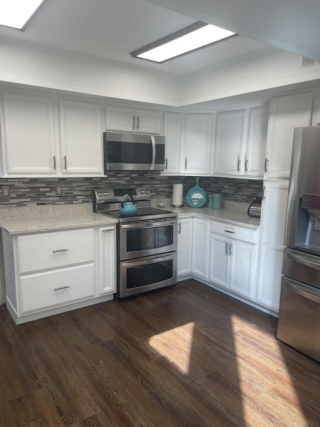 kitchen featuring white cabinets, appliances with stainless steel finishes, dark wood finished floors, tasteful backsplash, and visible vents