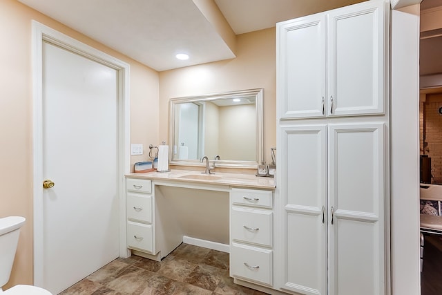 bathroom with vanity, toilet, stone finish flooring, and a closet