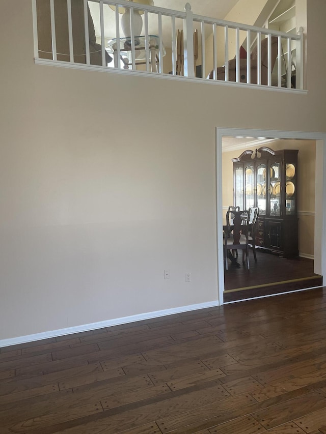 interior space featuring baseboards, a towering ceiling, and hardwood / wood-style flooring