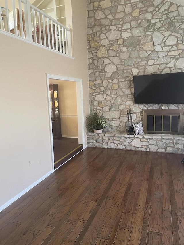 unfurnished living room with wood-type flooring, baseboards, and a glass covered fireplace