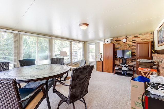 carpeted dining area with brick wall