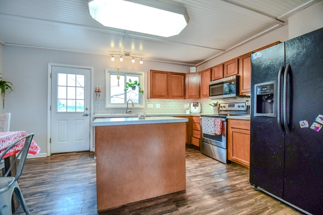 kitchen featuring sink, a center island, appliances with stainless steel finishes, dark hardwood / wood-style floors, and backsplash