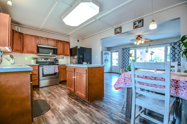 kitchen featuring appliances with stainless steel finishes, dark hardwood / wood-style flooring, a kitchen island, pendant lighting, and backsplash