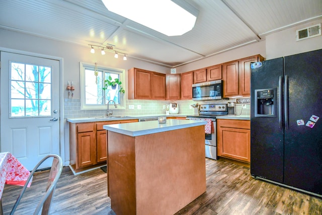 kitchen with sink, appliances with stainless steel finishes, dark hardwood / wood-style flooring, a kitchen island, and backsplash