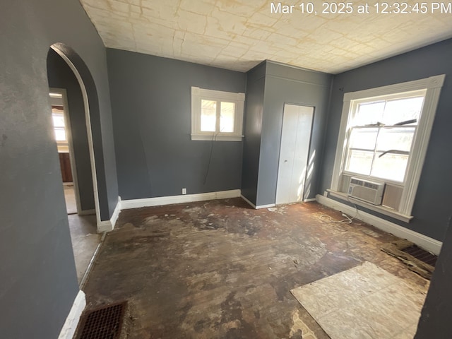 interior space with arched walkways, cooling unit, and baseboards