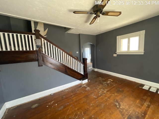 interior space featuring hardwood / wood-style floors, stairway, baseboards, arched walkways, and a textured ceiling