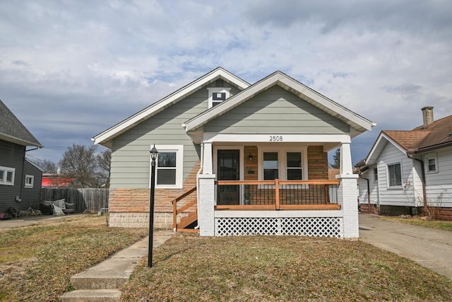 bungalow featuring fence, a front lawn, and a porch