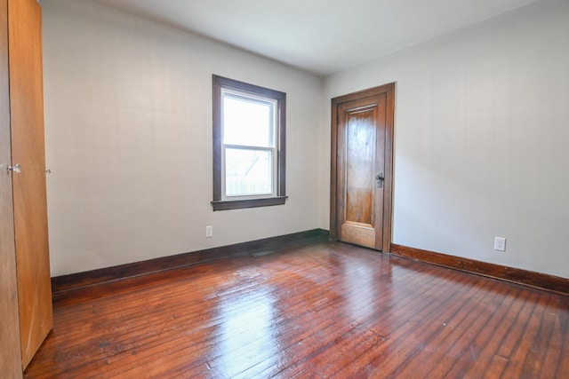 empty room with dark wood finished floors and baseboards