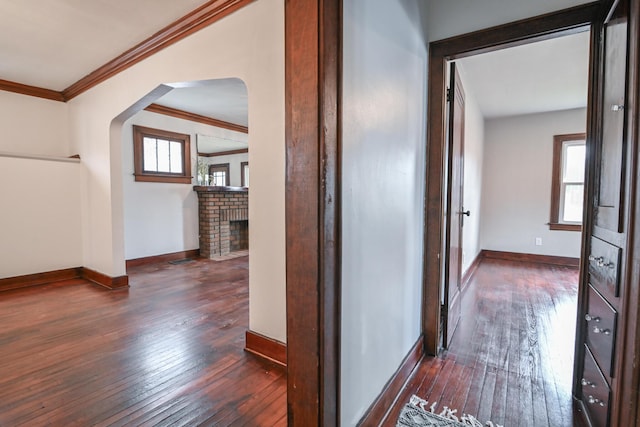 hallway with dark wood-style floors, arched walkways, ornamental molding, and baseboards