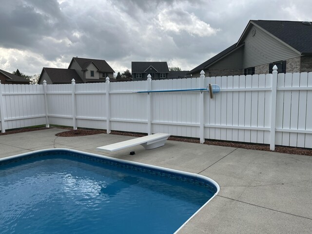 view of swimming pool with a fenced in pool, fence, a diving board, and a patio area