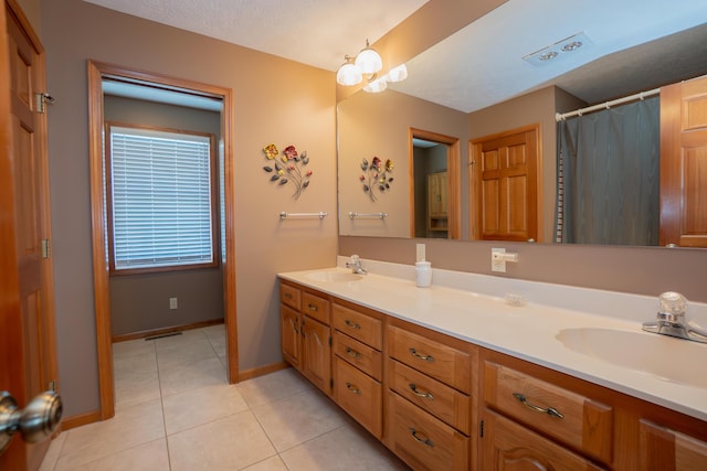 bathroom with a sink, baseboards, tile patterned flooring, and double vanity