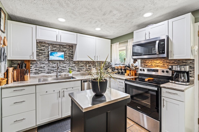 kitchen featuring stainless steel appliances, light countertops, white cabinets, and a sink