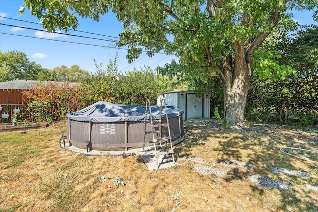 view of yard with fence, a storage unit, an outdoor pool, and an outbuilding