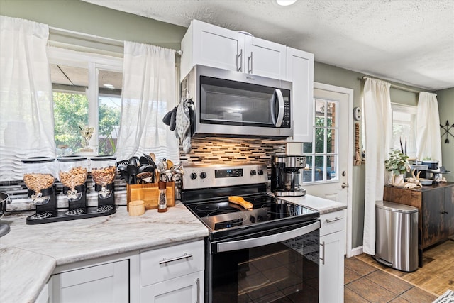 kitchen featuring decorative backsplash, stainless steel appliances, a textured ceiling, light countertops, and white cabinetry