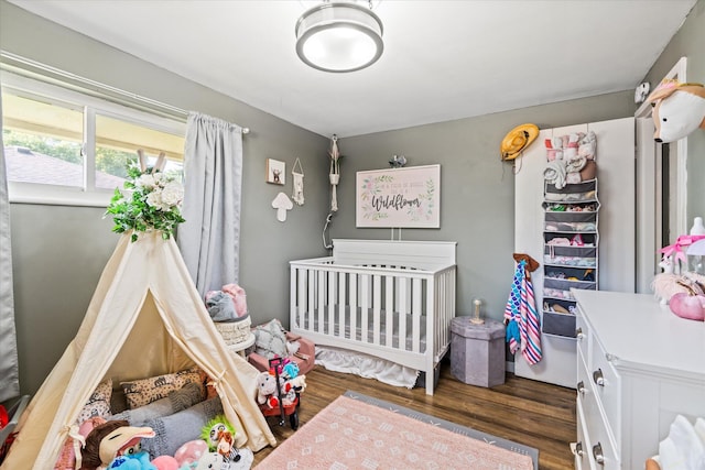 bedroom featuring a nursery area and wood finished floors