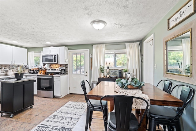 kitchen featuring light tile patterned floors, white cabinets, decorative backsplash, stainless steel appliances, and light countertops