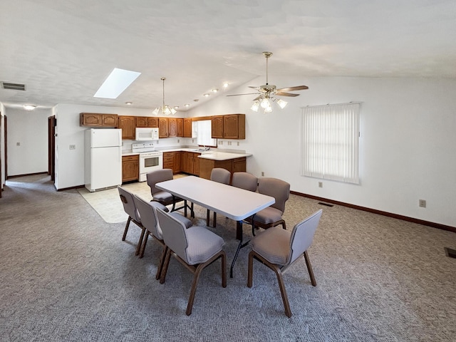 dining space with lofted ceiling with skylight, visible vents, light carpet, and baseboards