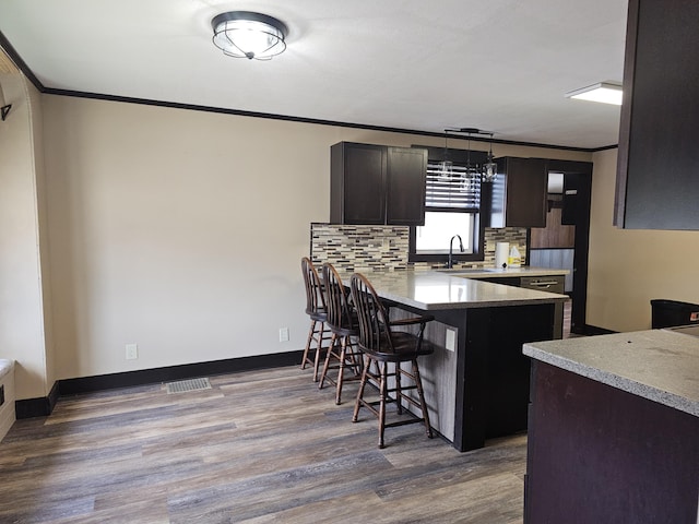 2 E Main St, Fletcher, OH 45326 - kitchen with a breakfast bar area, wood finished floors, crown molding, a peninsula, and backsplash
