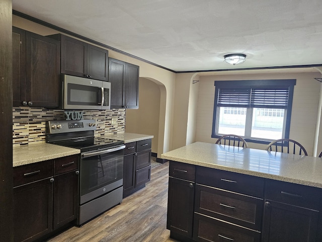 2 E Main St, Fletcher, OH 45326 - kitchen with appliances with stainless steel finishes, arched walkways, decorative backsplash, wood finished floors, and ornamental molding