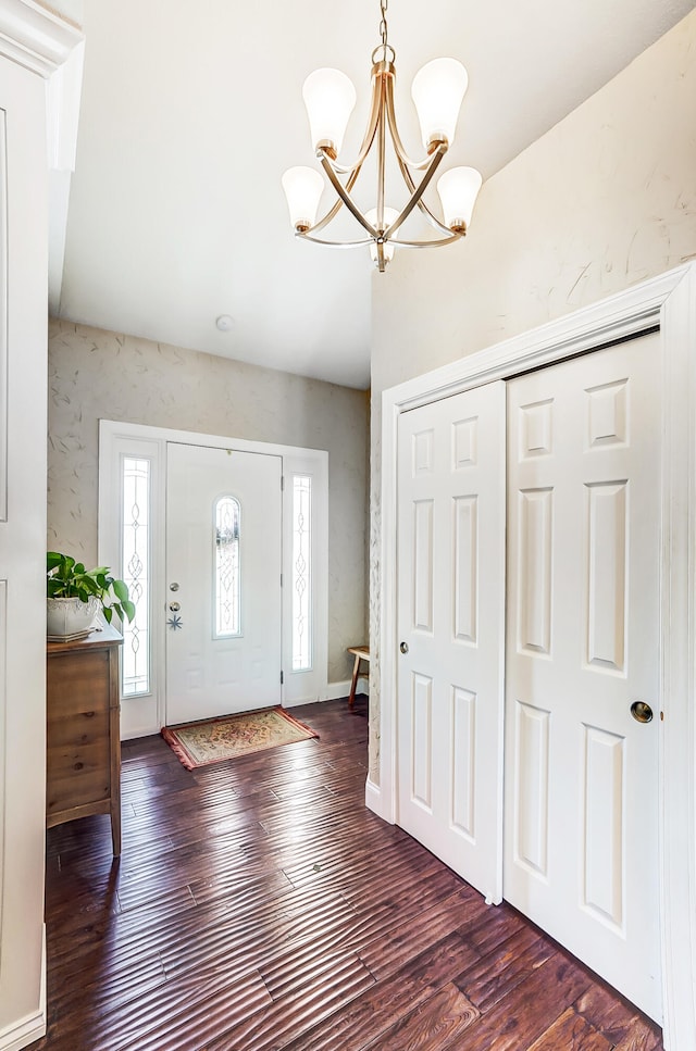 foyer with hardwood / wood-style floors, wallpapered walls, baseboards, and a chandelier