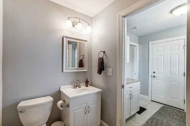 bathroom with vanity, baseboards, a textured ceiling, tile patterned floors, and toilet