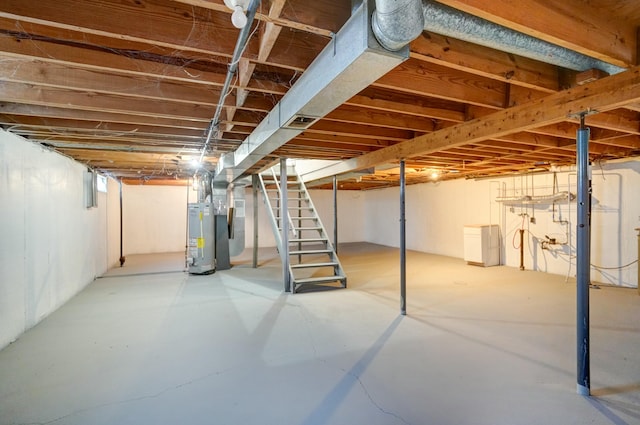 unfinished basement featuring stairs and water heater