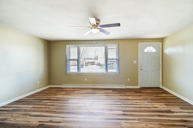 foyer with a wealth of natural light, baseboard heating, ceiling fan, and wood finished floors