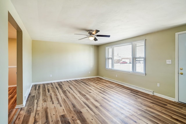 empty room with a ceiling fan, wood finished floors, baseboards, and baseboard heating