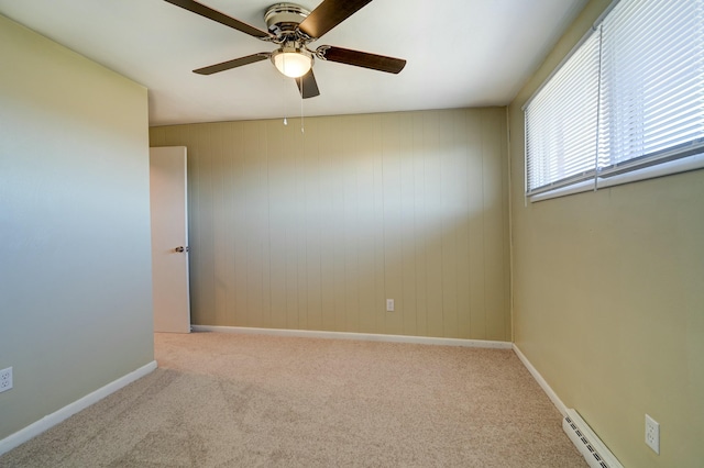 carpeted empty room with a baseboard radiator, baseboards, and ceiling fan