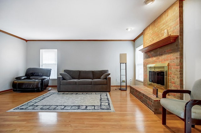 living room with a brick fireplace, ornamental molding, and light wood-type flooring