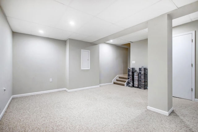 basement featuring a paneled ceiling and carpet flooring