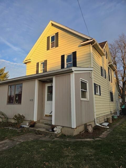 back of property featuring entry steps and a yard