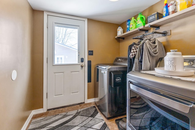 clothes washing area with baseboards, laundry area, and washer and clothes dryer