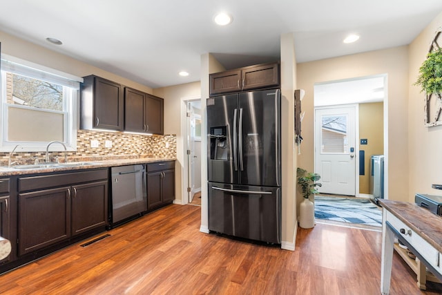 kitchen featuring tasteful backsplash, visible vents, wood finished floors, stainless steel appliances, and a sink