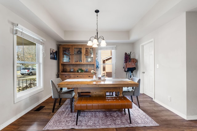 dining room with visible vents, baseboards, dark wood finished floors, an inviting chandelier, and a raised ceiling