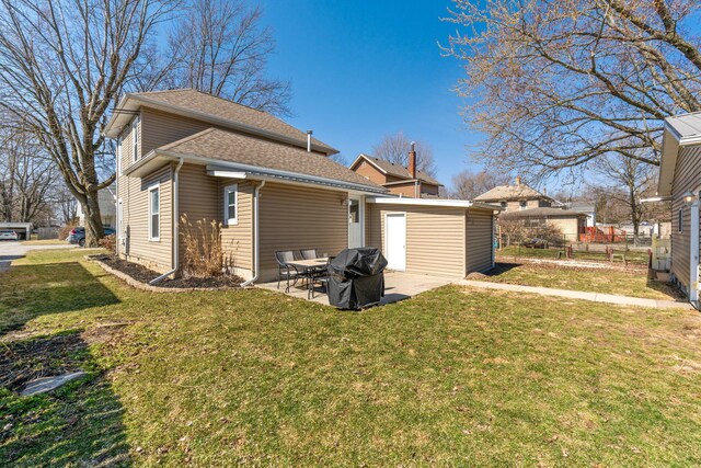 rear view of property with a lawn, a shingled roof, and a patio area