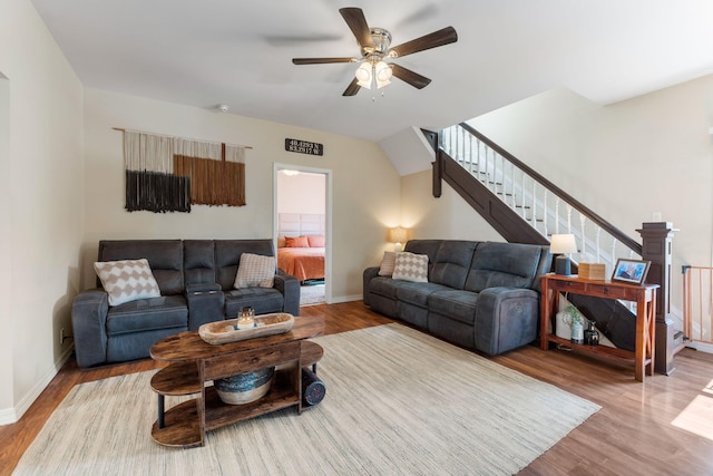 living room featuring baseboards, a ceiling fan, wood finished floors, and stairs