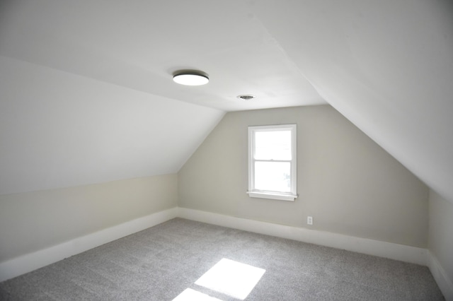 additional living space with visible vents, carpet, and vaulted ceiling