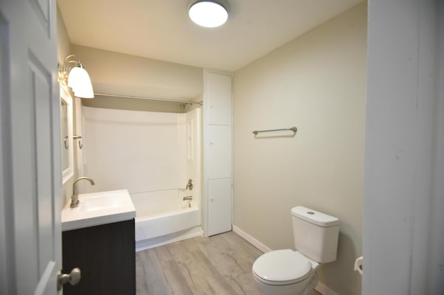 full bathroom featuring baseboards, shower / washtub combination, toilet, wood finished floors, and vanity