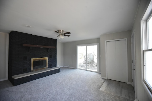 unfurnished living room featuring baseboards, carpet, a brick fireplace, and a ceiling fan