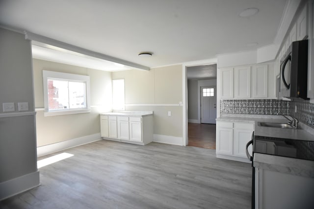 kitchen with a wealth of natural light, range, light wood-style floors, and black microwave