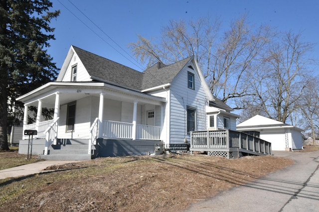 view of side of home with an outdoor structure, covered porch, a detached garage, and a shingled roof