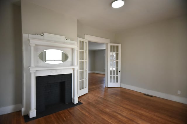 unfurnished living room with visible vents, baseboards, wood finished floors, and french doors