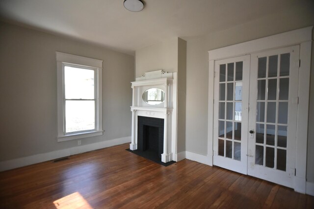 unfurnished living room featuring visible vents, baseboards, a fireplace with flush hearth, french doors, and dark wood-style floors