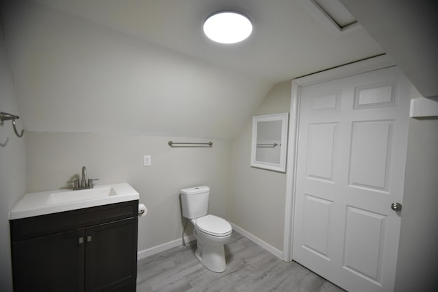 half bathroom with toilet, wood finished floors, baseboards, vanity, and vaulted ceiling