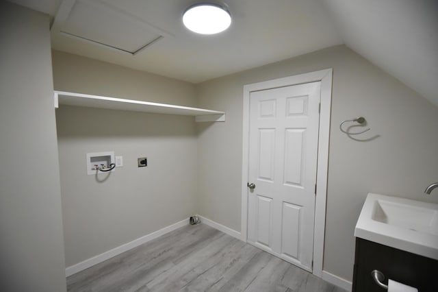 clothes washing area with baseboards, light wood finished floors, laundry area, electric dryer hookup, and a sink