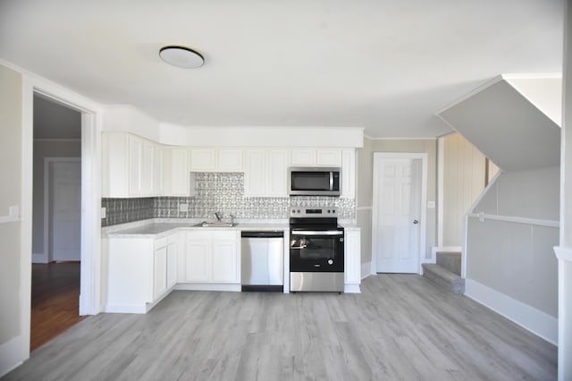 kitchen featuring backsplash, light countertops, light wood-style floors, stainless steel appliances, and a sink