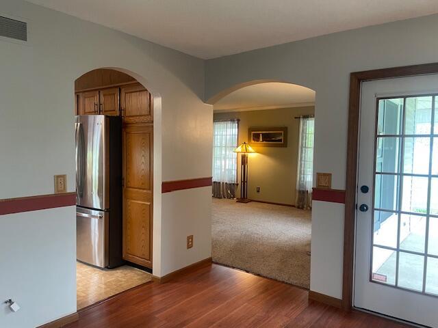 450 Yale Ave, Lima, OH 45804 - kitchen with freestanding refrigerator, light wood-style flooring, visible vents, arched walkways, and brown cabinets