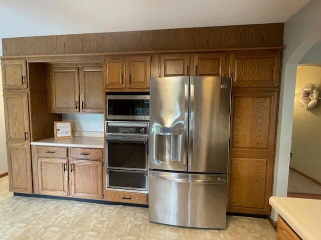 450 Yale Ave, Lima, OH 45804 - kitchen with brown cabinets, stainless steel appliances, arched walkways, a warming drawer, and light countertops