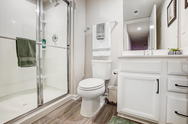 bathroom featuring hardwood / wood-style flooring, vanity, toilet, and a shower with door